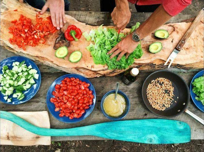 Hands preparing fresh vegetables on a wooden board